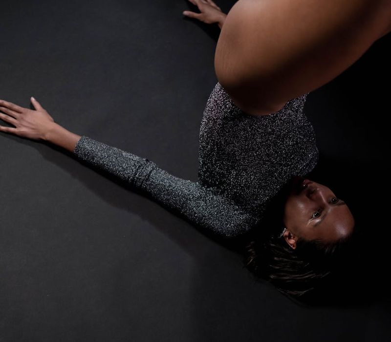 An athlete in high-contrast performing a focused stretch in a dark room
